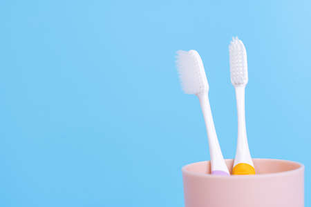 Closeup toothbrush in the glass isolated blue background. Copy space for text.の写真素材