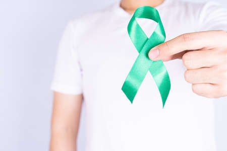 World kidney day, hands holding green ribbon awareness of kidney disease on chest isolated grey background.の写真素材