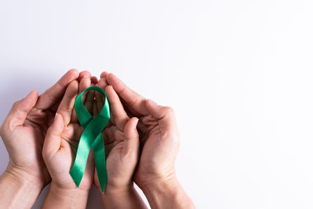 World kidney day, man and woman hands holding green ribbon awareness of kidney disease isolated...
