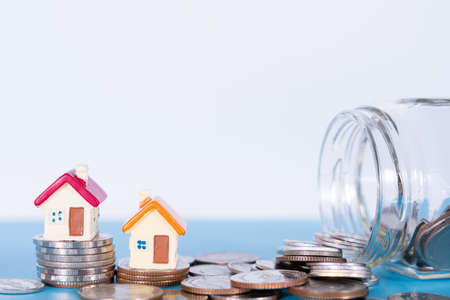 House and coins in jar isolated grey background. Property investment and house mortgage financial concept.の写真素材
