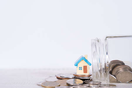 House and coins in jar isolated grey background. Property investment and house mortgage financial concept.の写真素材