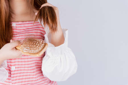 Closeup hand holding comb and hair fall problem isolated grey background.の写真素材