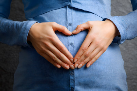 Pregnant belly with hands forming a heart shape.の素材