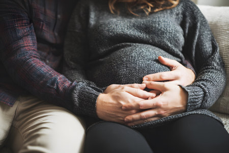 A pregnant belly is cradled by loving hands showing gentle care and anticipation.の素材