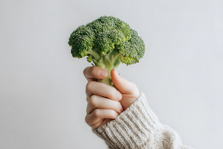 Vegan broccoli held by a hand showing healthy food choice.の素材