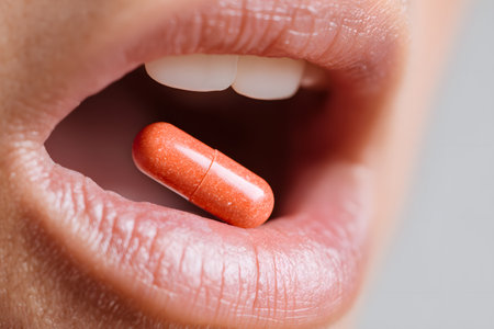 A pill rests on lips, about to be swallowed by an open mouth.の素材