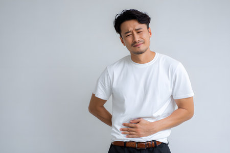 A man holds his stomach feeling pain.の素材