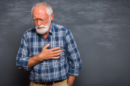 Older man feeling chest pain holds his heart with hand.の素材