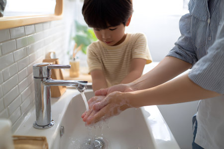 Child and adult hands washing with soap and water at sink.の素材