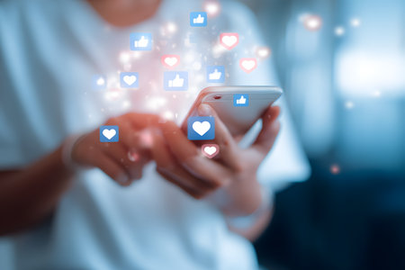 A person uses a mobile phone with social media likes and hearts appearing around the screen.の素材