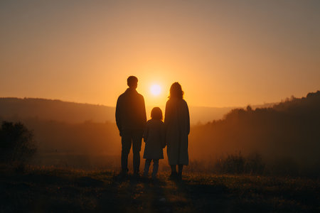 Silhouette family watching sunset over hillsの素材