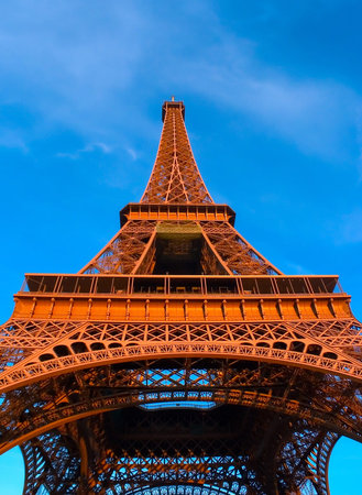 View from bottom of Eiffel Tower, lit by late afternoon sun.