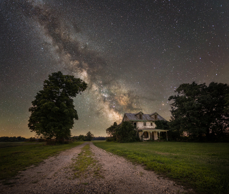 Dirt road leading to an abandoned home under the Milky Way Galaxyの写真素材