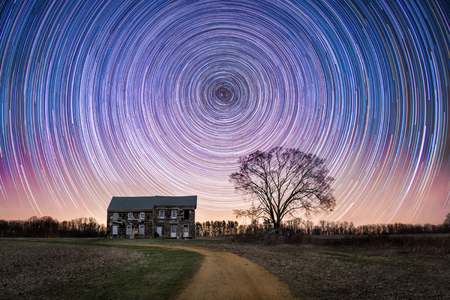 Star trails over an abandoned farm houseの写真素材