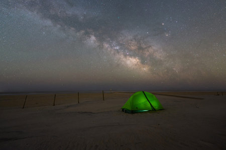 Milky way Galaxy rising over a lit tentの写真素材