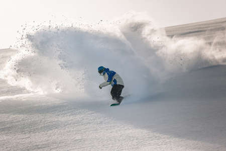A man snowboarder at speed bends and brakes, splashing loose deep snowのeditorial素材