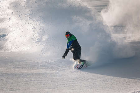 A man snowboarder at speed bends and brakes, splashing loose deep snowのeditorial素材