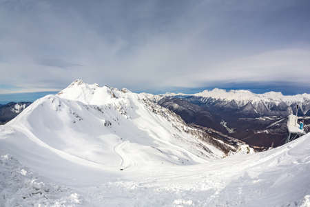 Snow-covered mountain ranges covered with coniferous forests in the cloudsの写真素材