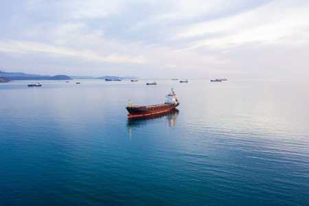 Bulk carrier ship at anchor in orange sunset, aerial view. Colored skyの写真素材