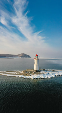 Aerial view of the lighthouse in winter in the ice at dawnの写真素材