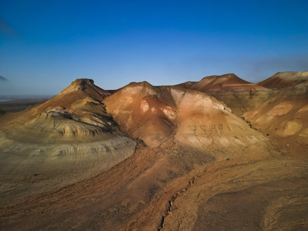 Warm sunrise highlights the distinct bands of Aktumsuk hills in Karakalpakstan