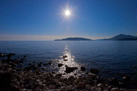 Blue landscape with the sun. Sunset sea romantic landscape with bright saturated colors, sea and rock stones.の写真素材