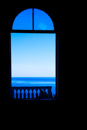 The window from which comes a bright light and a blue sky can be seen. Clear shadows, ruins, an abandoned hotel. symbol of despair and hope.の写真素材