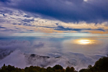 Evening landscape is a sea of clouds and the sunset sun is reflected in the sea, the view from the high mountain on the sea shore. Abkhazia, Gagra.の写真素材
