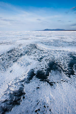 Zigzag of transparent blue-turquoise ice blue sky and hills on Lake Baikalの写真素材