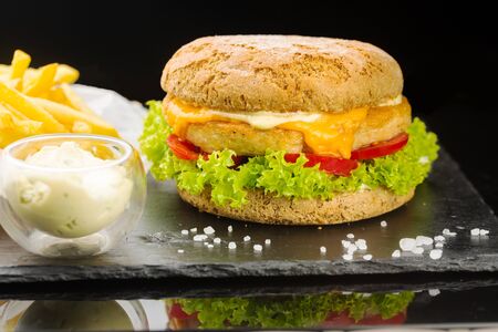 pork burger with ketchup and french fries. wooden board on black backgroundの写真素材