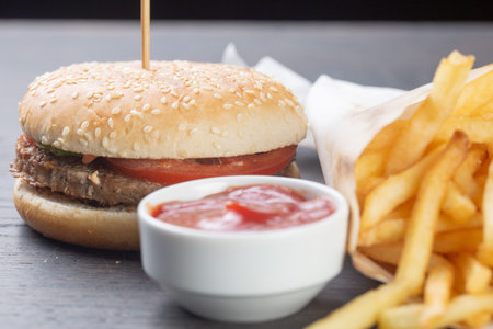 cheeseburger with beef patty with french fries and ketchup on a black background