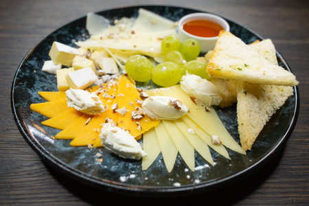 assorted cheese. thin sliced ??cheese with grapes crispy croutons of white bread with honey and...
