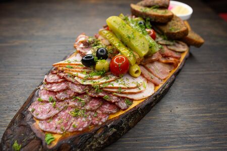 cold cuts of sausage, bacon and ham with pickled vegetables cherry tomatoes salted cucumber, black bread croutons with horseradish and mustard sauceの写真素材