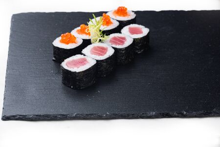 Maki sushi with salmon, red caviar and cream sauce on a stone board. on a white backgroundの写真素材