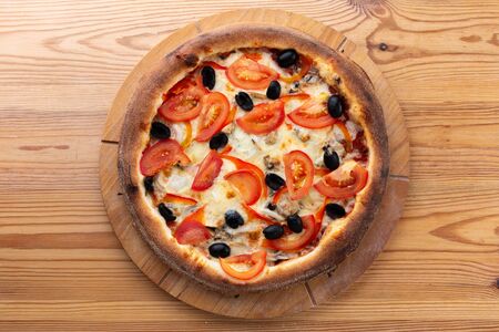 hearty italian pizza on a wooden board.
crispy cheese pizza with tomatoes, olives and mushroomsの写真素材