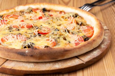 hearty italian pizza on a wooden board. 
meat pizza with beef, fresh tomatoes, mushrooms and grated cheeseの写真素材
