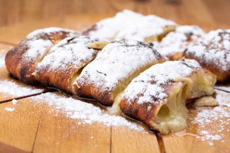 fruit strudel on a wooden board sprinkled with icing sugar. delicious pastriesの写真素材