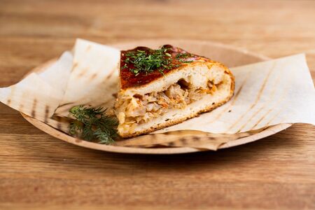 pie with stewed cabbage and carrots sprinkled with herbs on a disposable plateの写真素材