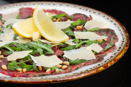 tender beef carpaccio and thin slices of cheese, nuts and a slice of lemonの写真素材