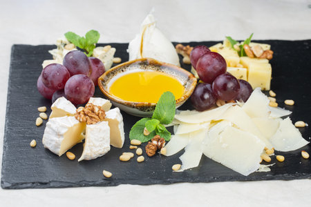 Set of cheese with nuts on wooden board over white concrete background, top view.の写真素材