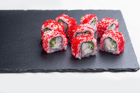Sushi roll with salmon, red avocado caviar and cheese on a black stone plate on a white plate. Sushi menu. Japanese food.の写真素材