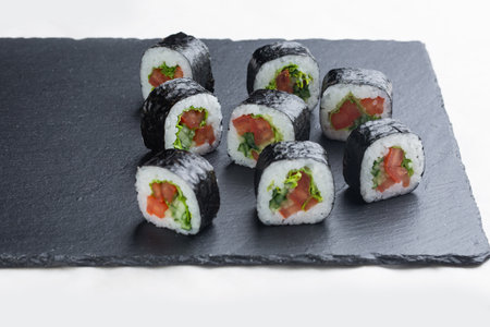 Sushi roll with salmon, avocado and cheese on a black stone plate on a white plate. Sushi menu. Japanese food.の写真素材