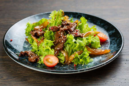 salad of stewed beef, lettuce, pickled peppers and cherry tomatoes. beef salad on a blue marble plateの写真素材