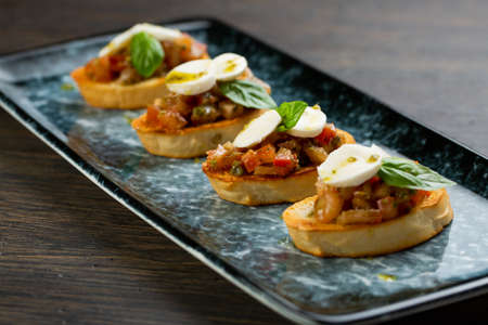vegetable bruschetta with egg and cheese on white toasted bread. bruschetta on a blue plateの写真素材