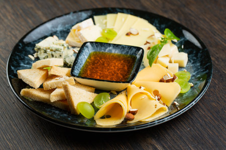 cheese plate with green grapes, crunchy croutons and nuts. set of different types of cheese with honey on a marble plateの写真素材