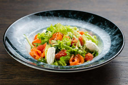 Greek salad of tomatoes, pickled peppers, cucumbers, lettuce and feta cheese. greek salad with olives and white sesame seeds on a blue marble plateの写真素材
