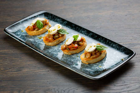 vegetable bruschetta with egg and cheese on white toasted bread. bruschetta on a blue plateの写真素材