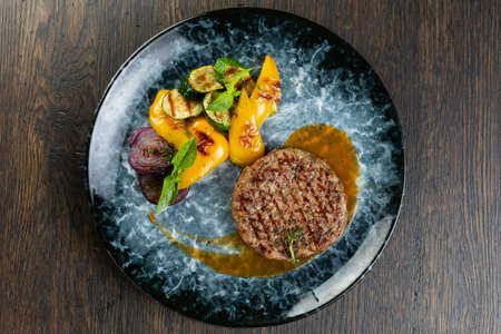 grilled minced beef cutlet with grilled vegetables and barbecue sauce. fried zucchini, onion and pepper with minced pork cutletの写真素材