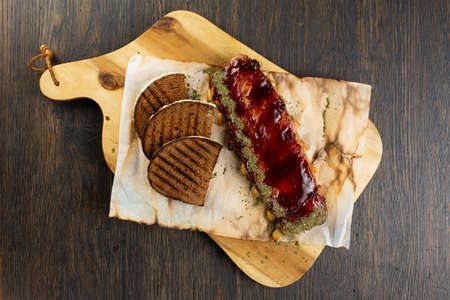 grilled pork ribs with barbecue sauce and grilled bread slices. pork with tomato spice sauce on a wooden boardの写真素材