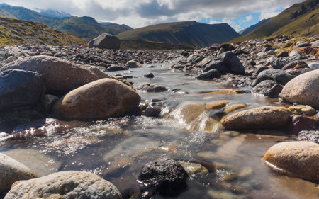 Closeup shot of a river stream with round stones and distant mountains. Shalow depth of fieldの写真素材